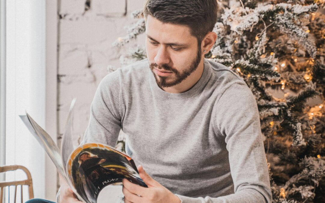 man reading a magazine, sitting under a Christmas tree